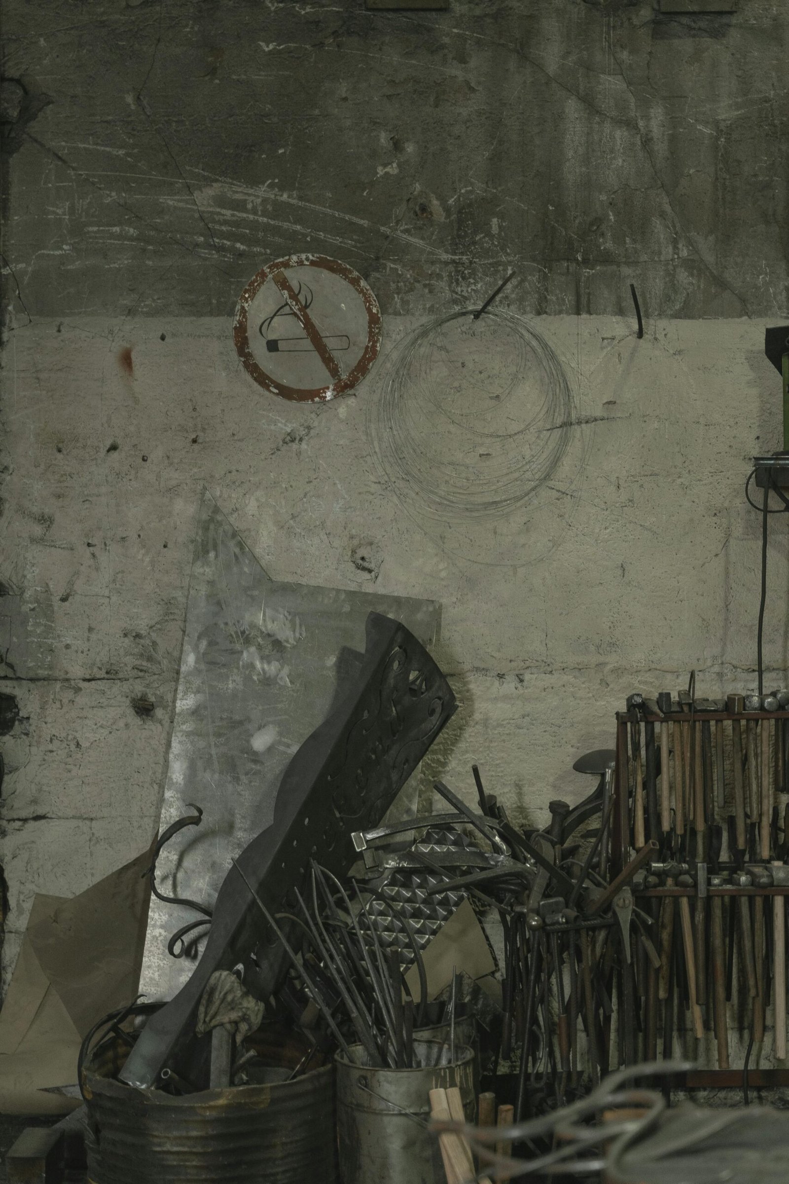 A collection of metal scraps, tools, and steel components in a dimly lit warehouse corner.